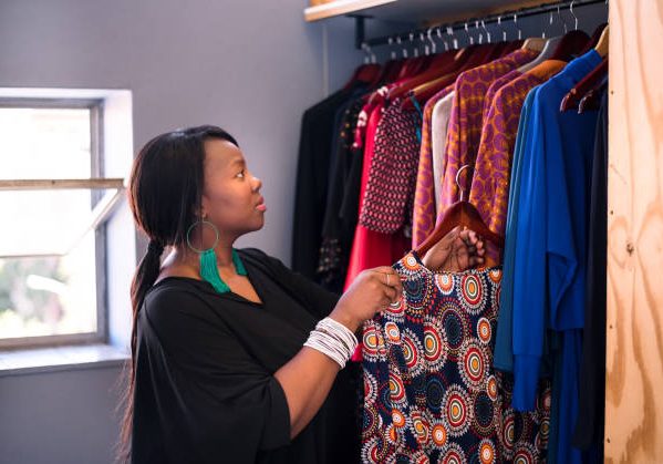 Shot of a female dressmaker arranging the dresses in the rack at fashion atelier